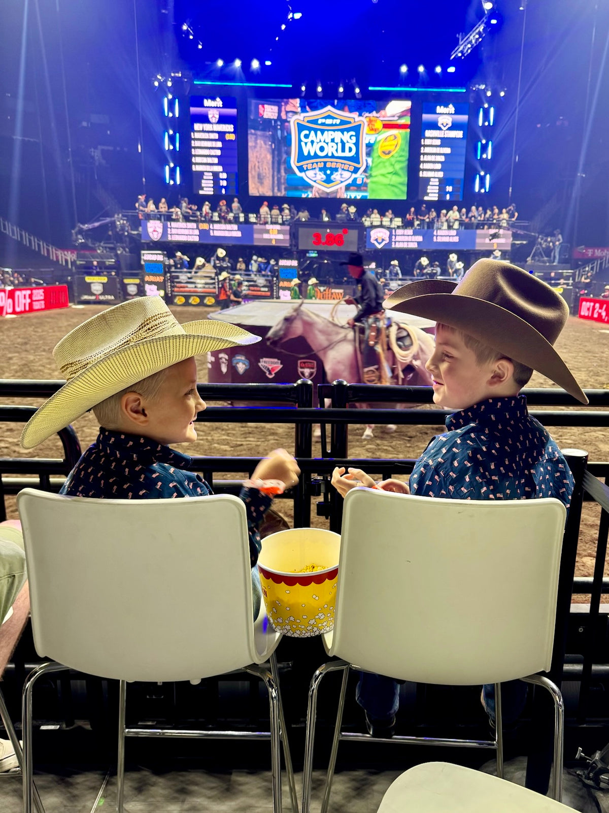 Two young boys in cowboy hats watching a rodeo
