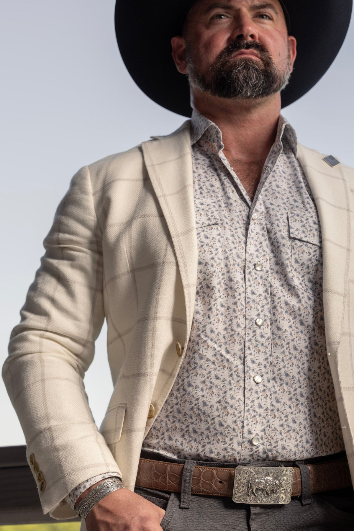 Man in a black felt hat and western jacket wearing a Clint Orms sterling silver buckle