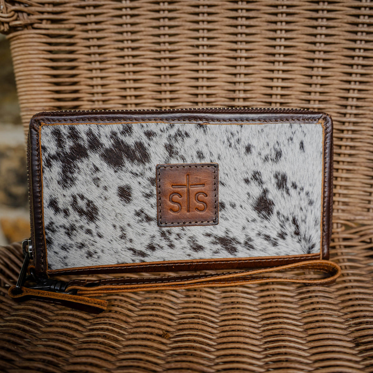 STS Ranchwear Women's Vaquero Cowhide Concho Bifold Wallet, Brown and White Hair-On – lifestyle on wicker chair