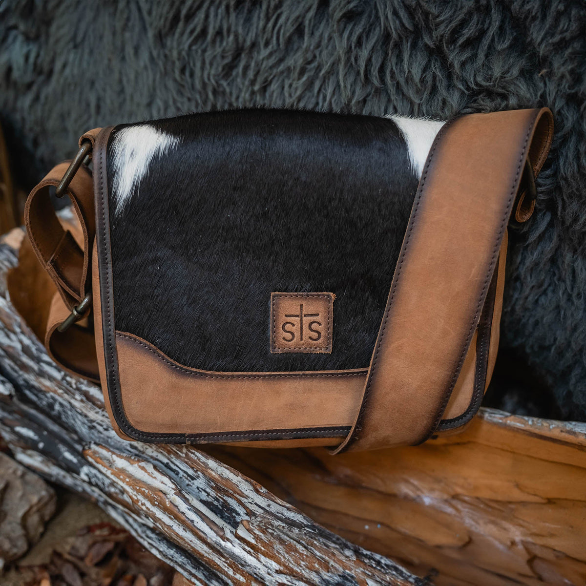 STS Ranchwear Cowhide Della Crossbody bag made of authentic cowhide leather with adjustable strap and rustic stitching details.