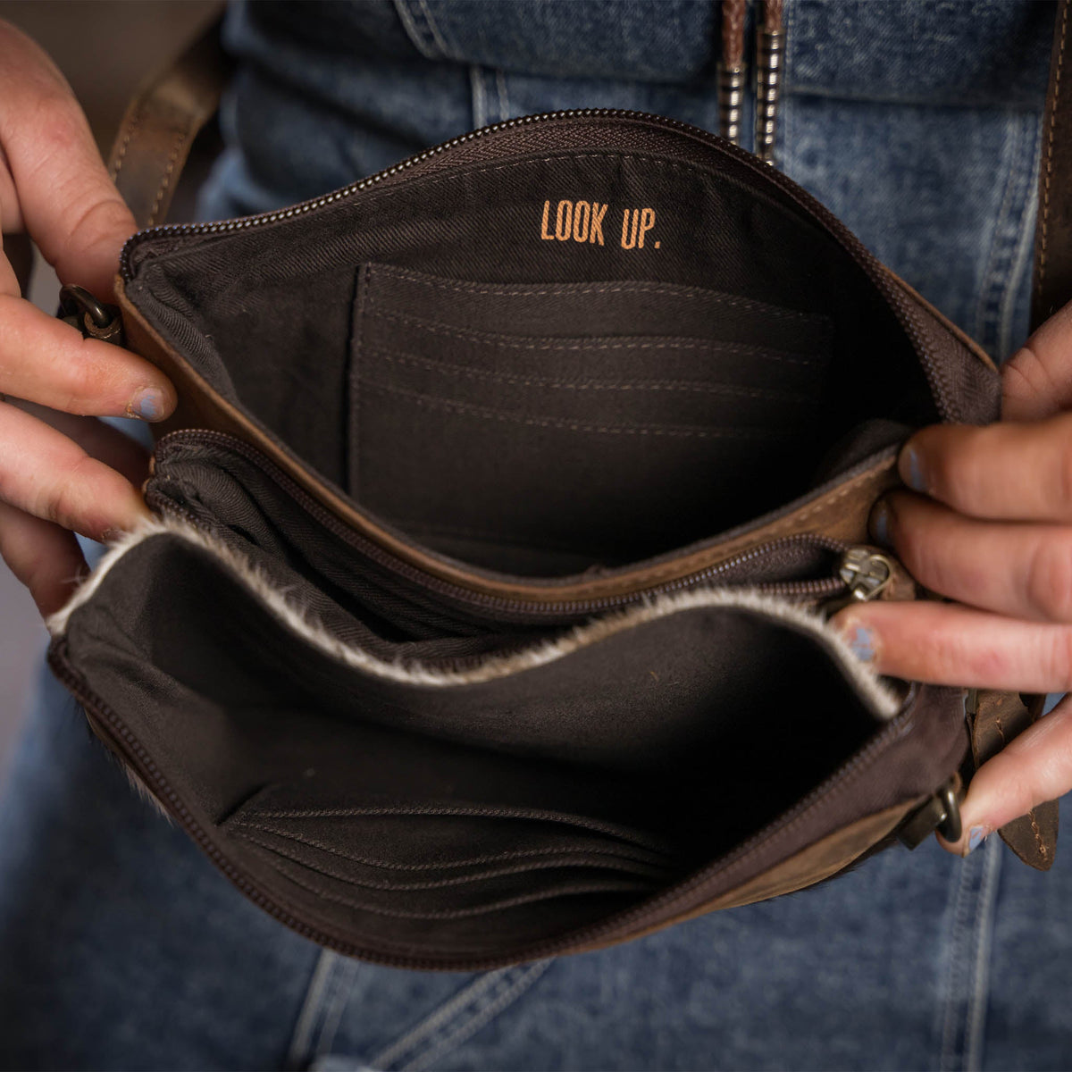 STS Ranchwear cowhide Rio crossbody bag with adjustable strap and rustic leather details, showcasing its handcrafted design.