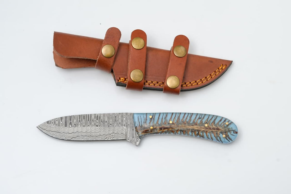 Custom Damascus steel knife with blue resin and bone handle by Titan International K, featuring a detailed blade and elegant handle design.