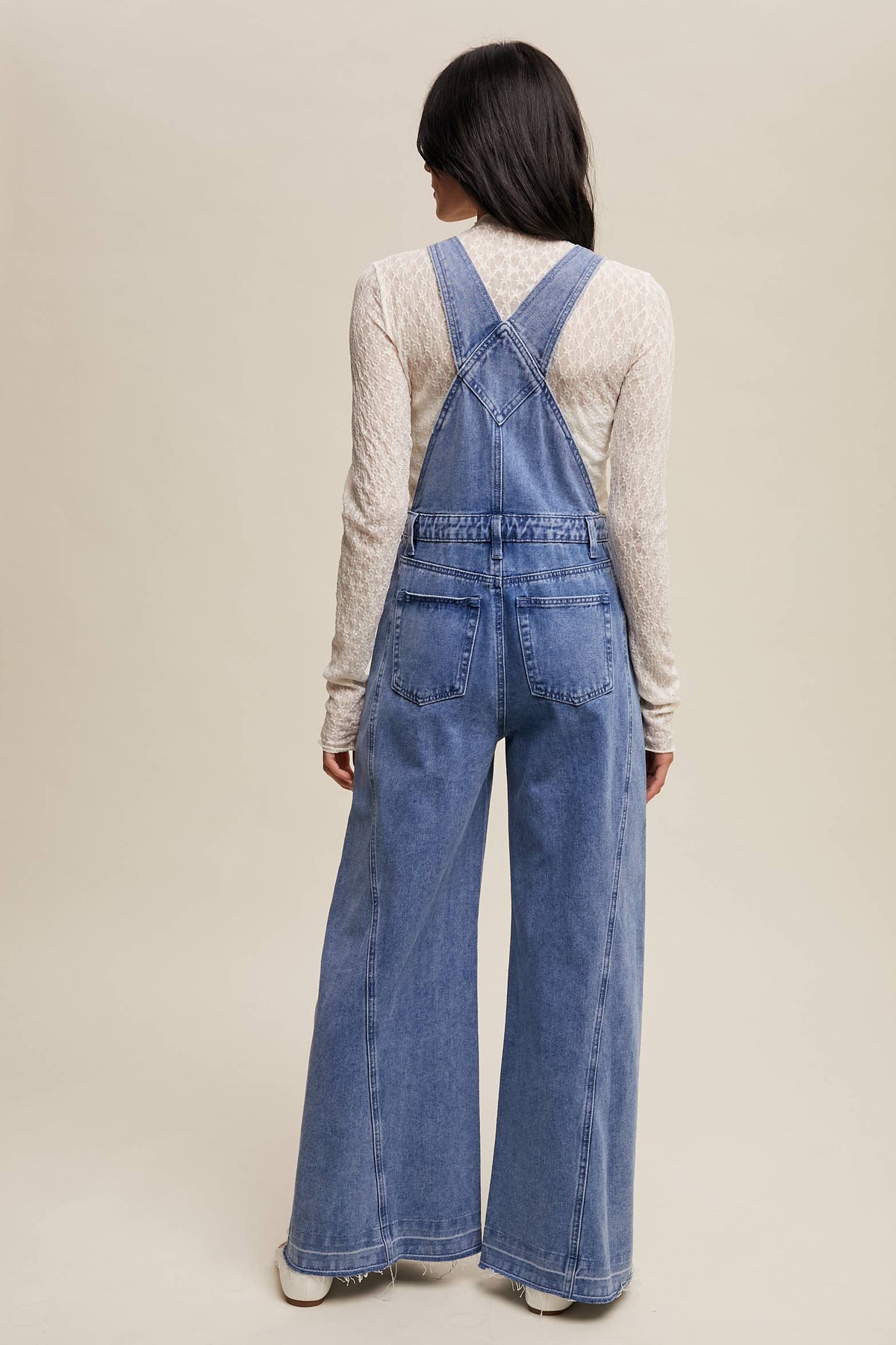 Wide-leg denim overalls by Listicle featuring a relaxed fit and classic blue wash, shown on a model.