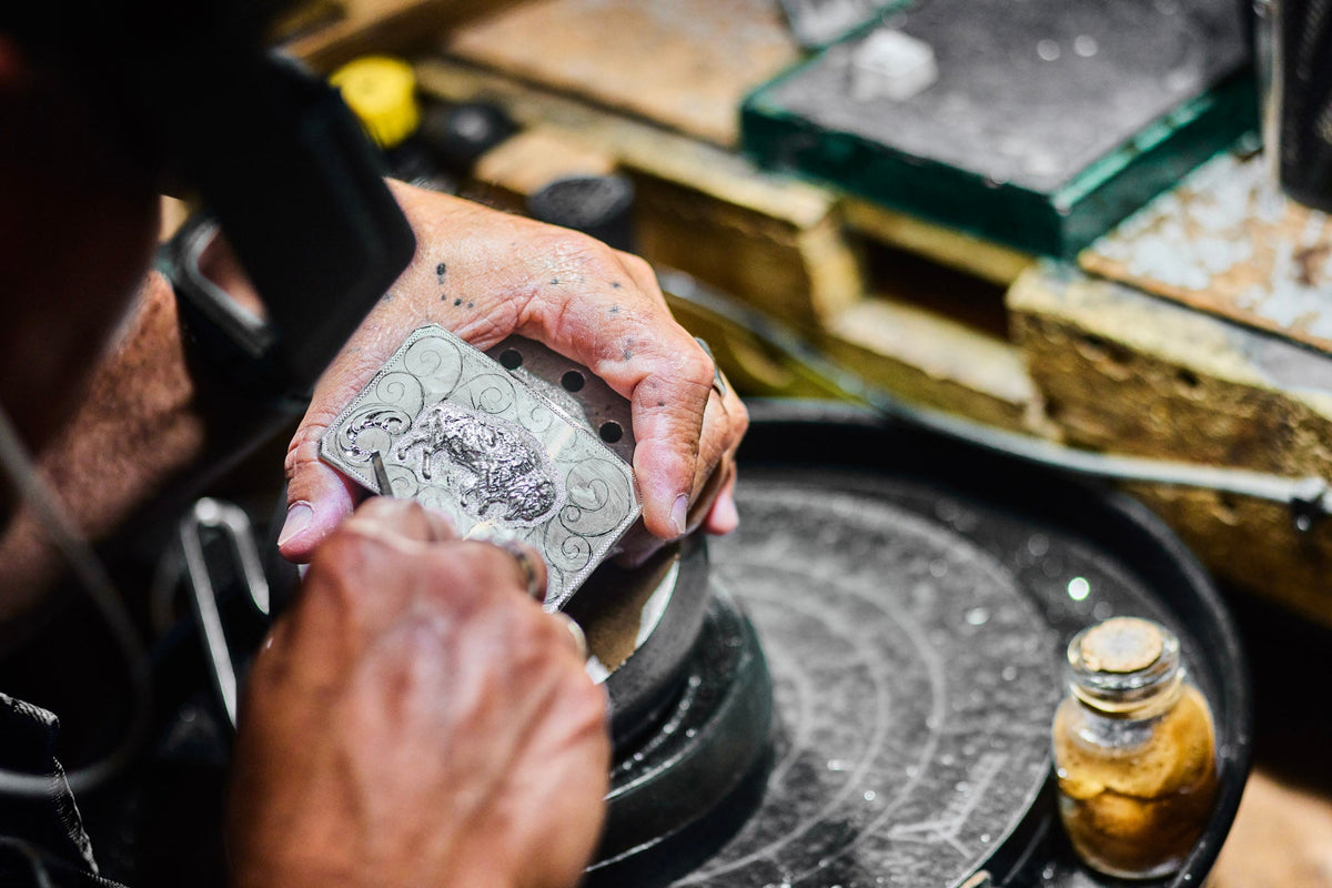 Silversmith hand-engraving a Clint Orms sterling silver buckle at the bench in Kerrville, Texas