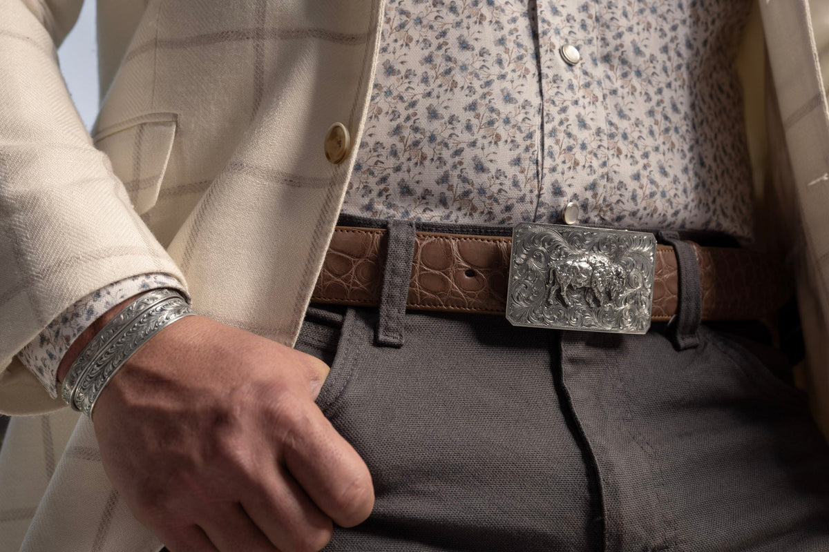 Man in a tweed vest wearing a Clint Orms sterling silver buckle on a tooled leather belt