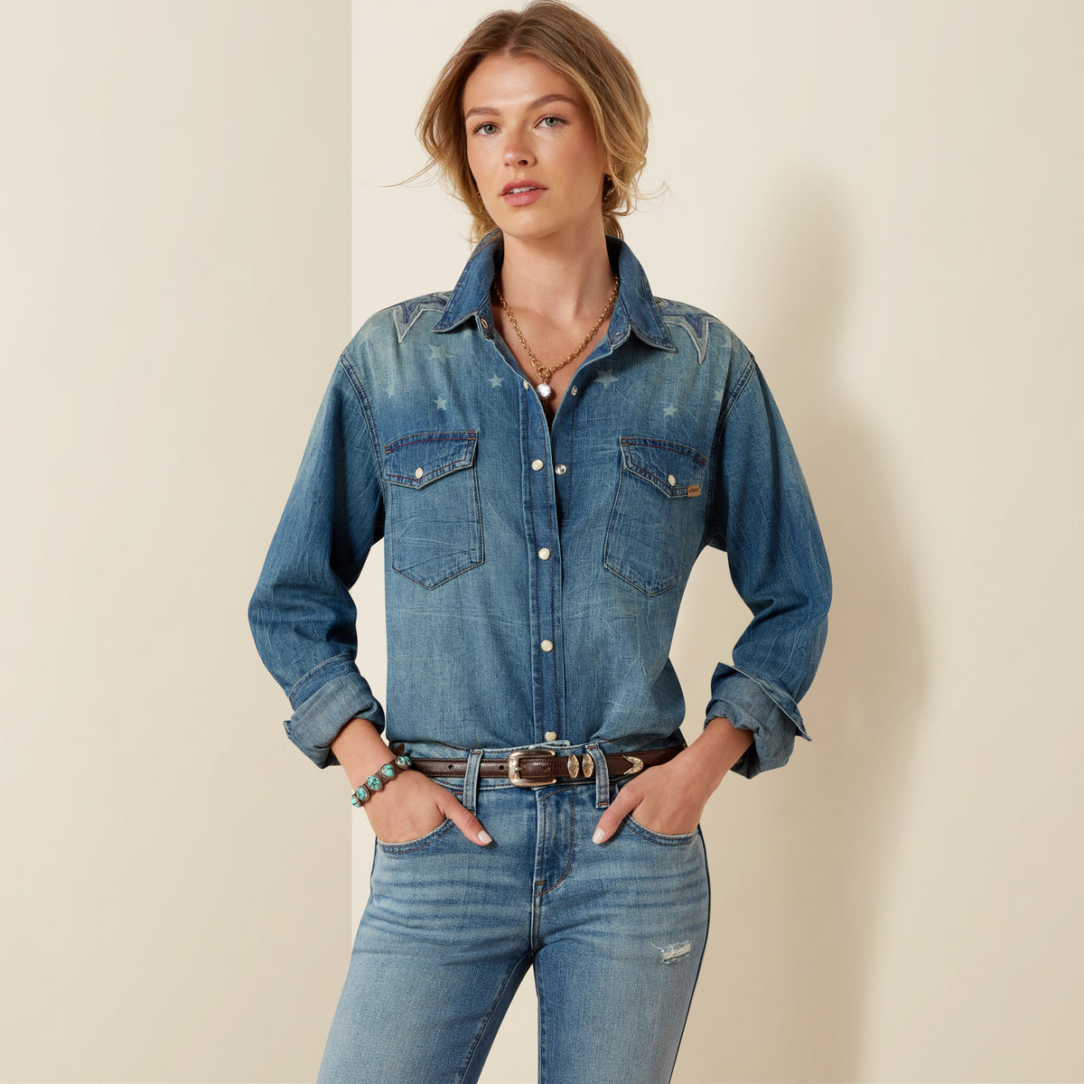 Ariat Women's Americana Denim Shirt in blue, featuring classic button-up style with chest pockets and long sleeves.