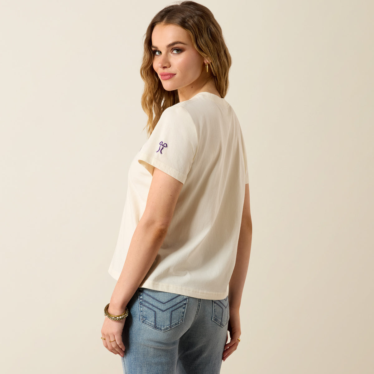 Ariat Women's Collegiate Darlin short sleeve T-shirt in cream and purple, casual shirt with crew neck and graphic design.