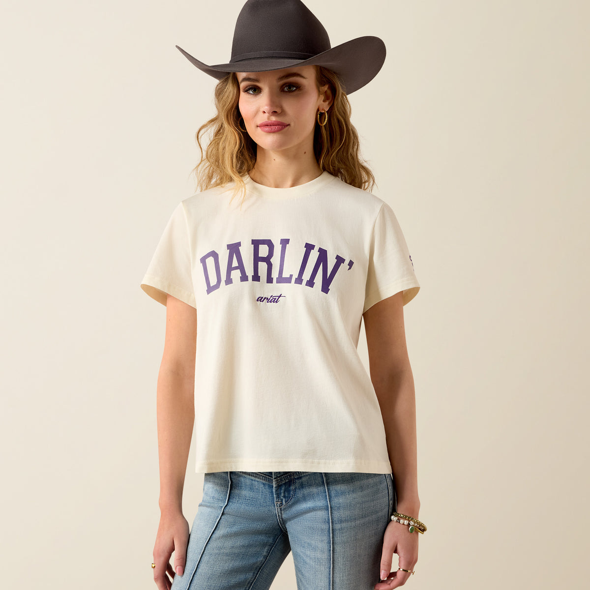Ariat Women's Collegiate Darlin short sleeve T-shirt in cream and purple, casual shirt with a relaxed fit and crew neckline.