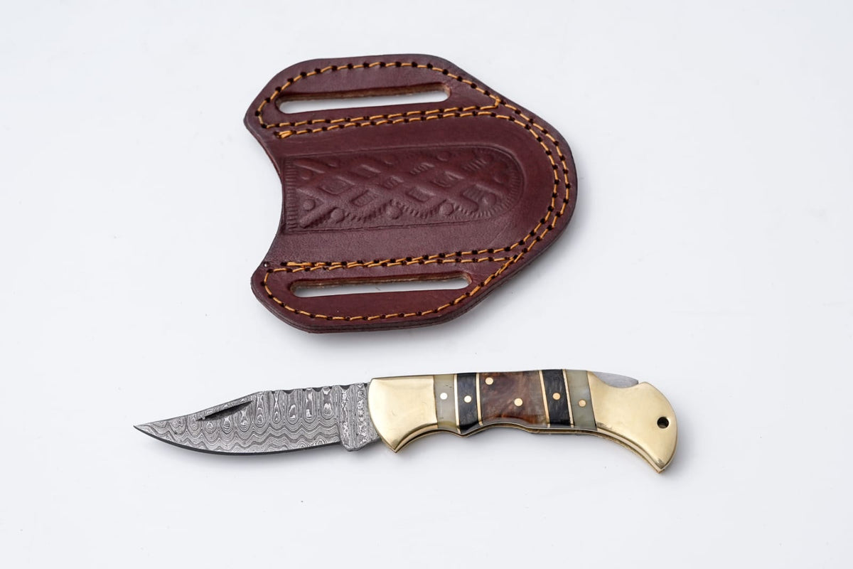 Titan International K brass and bone Damascus folding knife with leather sheath, detailed handle and sharp blade.