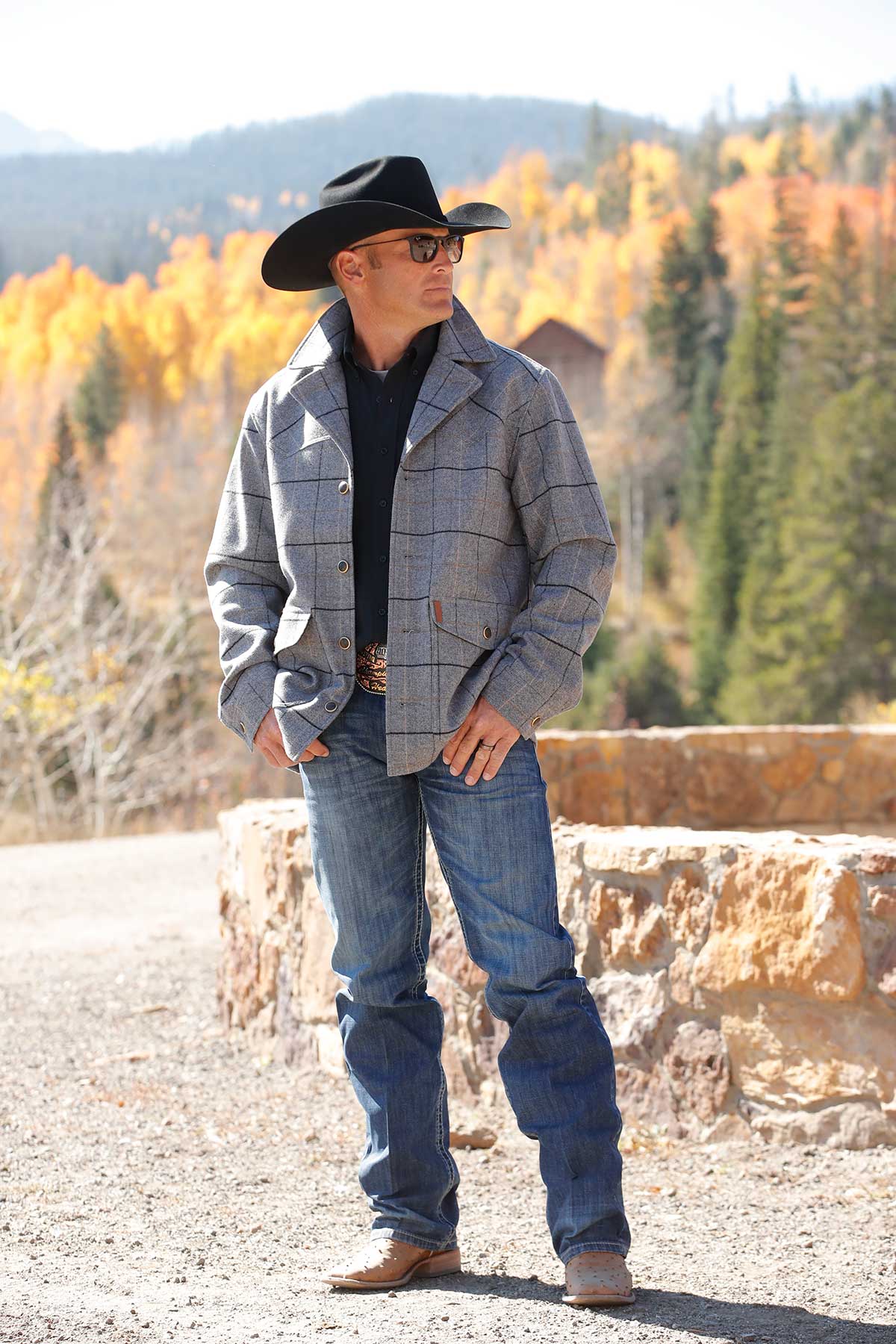 Man in a Cinch gray plaid wool jacket, jeans and black cowboy hat by fall aspens
