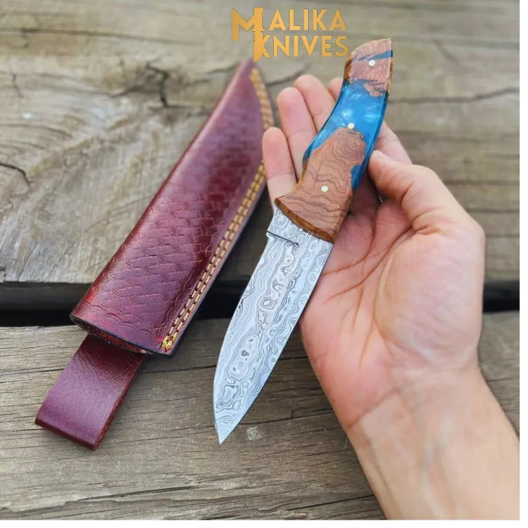 Malika Knives Damascus Steel Skinner Knife with rosewood and resin handle, leather sheath, ideal for outdoor use.