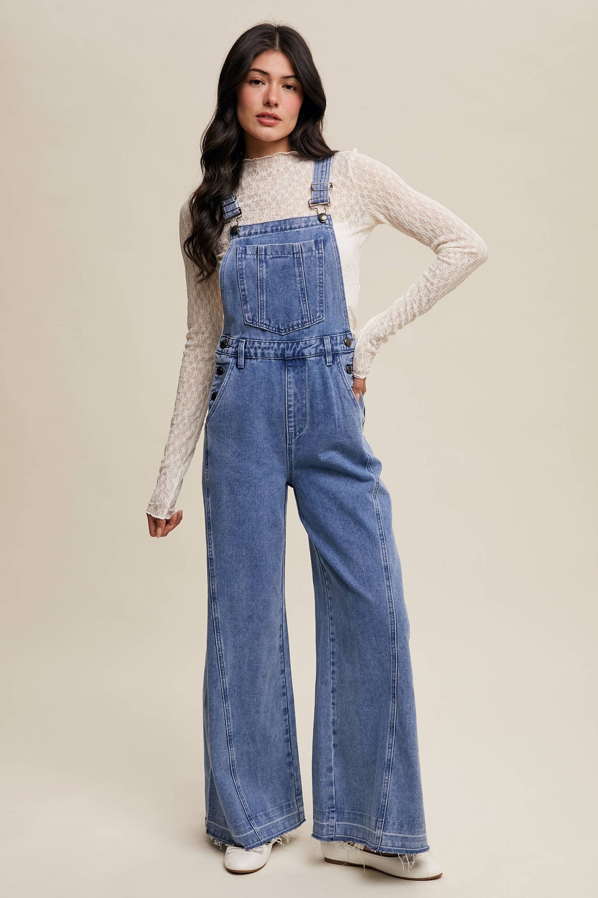 Wide-leg denim overalls by Listicle featuring adjustable straps and front pockets, styled on a model.