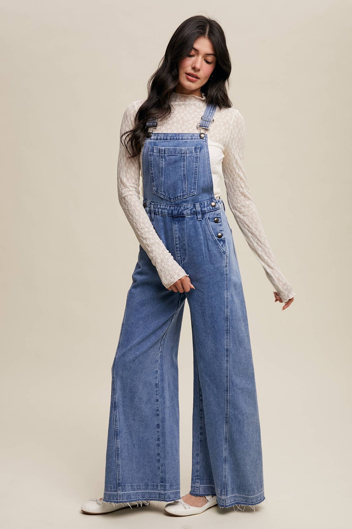 Wide-leg denim overalls by Listicle featuring adjustable straps and front pockets, styled on a model.