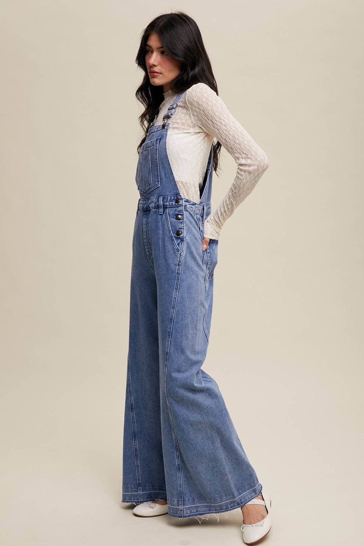 Wide-leg denim overalls by Listicle featuring a relaxed fit and classic blue wash, shown on a model with adjustable straps.
